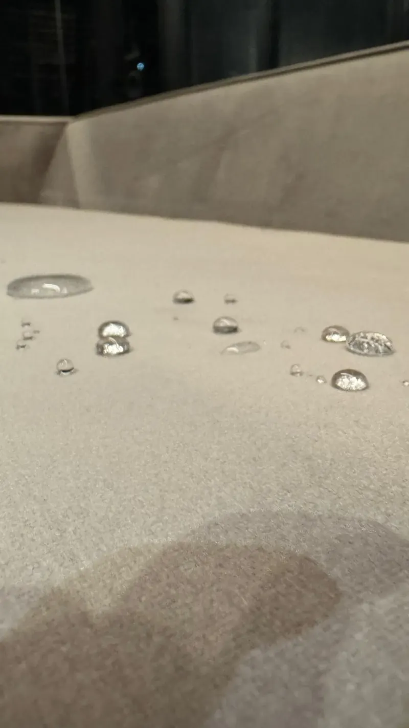 Gotas de água sobre tecido impermeabilizado pela SofáBrilho — efeito hidrofóbico real